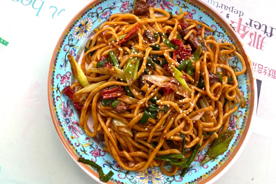 Close-up of authentic Xinjiang dry-fried noodles with hand-pulled noodles, lamb, onions, green peppers, red chili, and cumin being stir-fried in large wok, visible wok smoke, traditional Uyghur restaurant kitchen in Xinjiang, realistic food documentary photography, warm lighting, highly detailed texture, horizontal composition Close-up of authentic Xinjiang dry-fried noodles with hand-pulled noodles, lamb, onions, green peppers, red chili, and cumin being stir-fried in large wok, visible wok smoke, traditional Uyghur restaurant kitchen in Xinjiang, realistic food documentary photography, warm lighting, highly detailed texture, horizontal composition