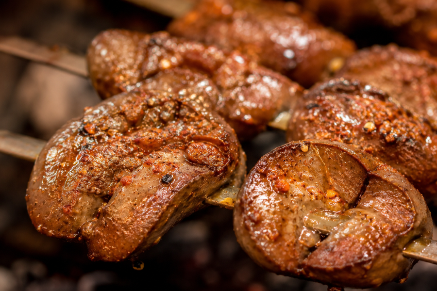 Close-up texture of Xinjiang-style grilled lamb kidney skewers with charcoal grill marks