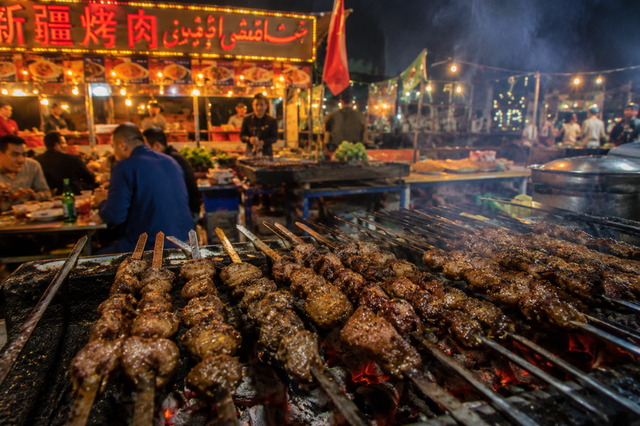 Xinjiang grilled lamb kidney skewers cooking over charcoal at a Uyghur night market