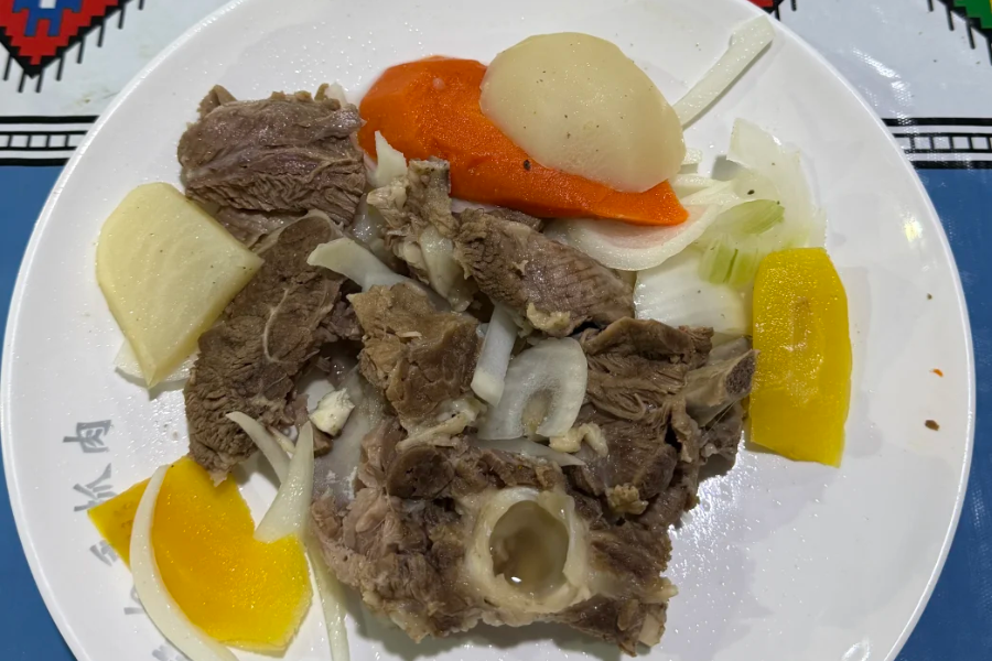 Traveler eating boiled lamb with onion and naan in Xinjiang, traditional hand-eaten lamb meal experience
