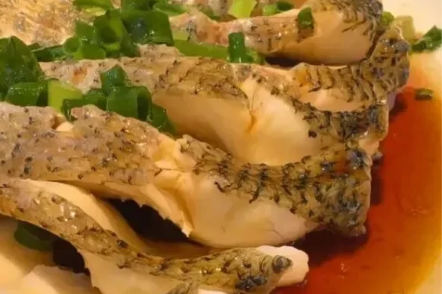 Tender Xinjiang grilled fish cube showing soft texture and chili glaze coating