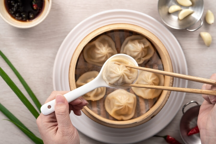 Xiaolongbao soup dumplings in bamboo steamer, black vinegar and ginger, Shanghai regional Chinese dish for travelers Xiaolongbao soup dumplings in bamboo steamer, black vinegar and ginger, Shanghai regional Chinese dish for travelers