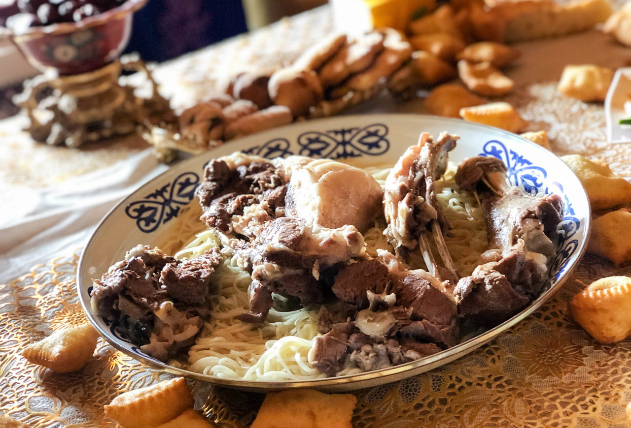 Boiled Lamb served in Xinjiang traditional dining setting, boiled lamb platter with onions and naan in a rustic Uyghur restaurant